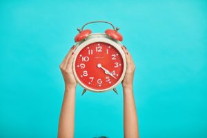 A person holds up a clock to prepare for daylight saving time