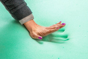 A hand pressing down on a memory foam mattress