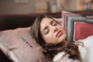 a woman sleeps on her back with her neck propped by a pillow