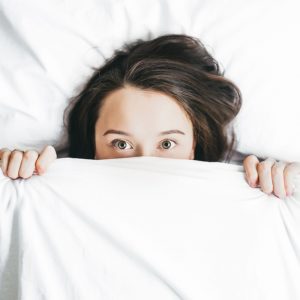 A woman covers half of her face with a white blanket to lessen her snoring