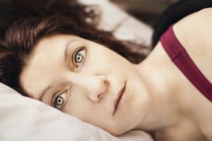 a woman lies awake suffering from sleep apnea