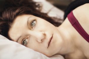 a woman lies awake suffering from sleep apnea